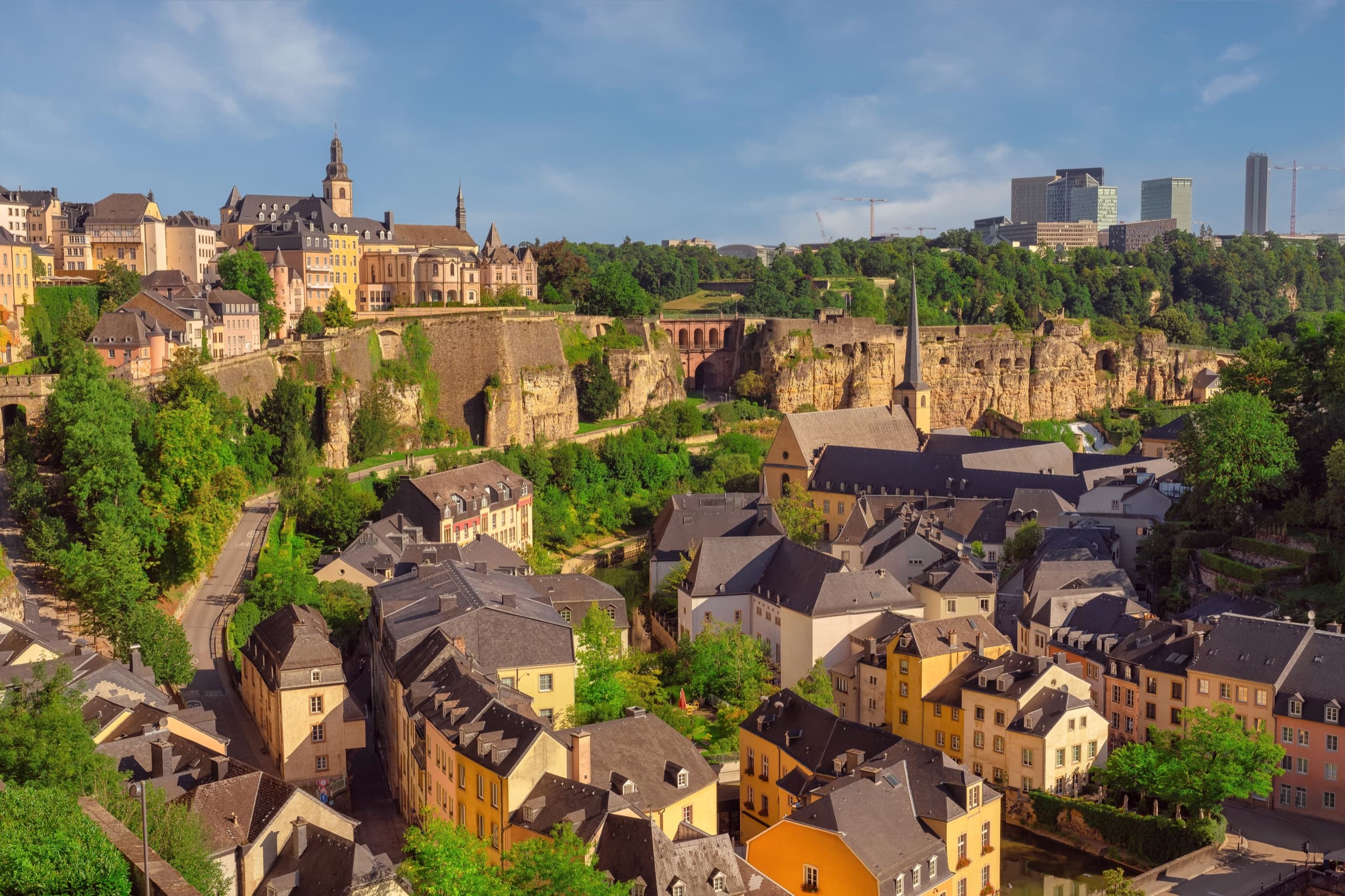 Scenic view of Luxembourg City with historic buildings and architecture along the fortification walls, featuring the old town's characteristic stone buildings and a bridge